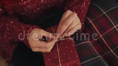 紧紧<strong>抓</strong>住女人的双手，完成圣诞红色礼物盒的包扎胶带，并绑在一个<strong>蝴蝶</strong>结握住盒子的概念。